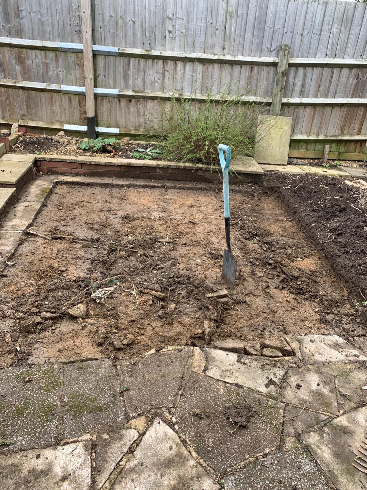 Overgrown garden cleared back to bare soil ready for landscaping